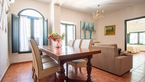 A dining area with a wooden table and chairs, a sofa, a chandelier, and artwork on the walls. - Self catering Puerta del Agua for 6 people (Uclés)