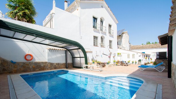 A swimming pool with a curved edge, a lifebuoy, and a stone wall. - Self catering Puerta del Agua for 6 people (Uclés)