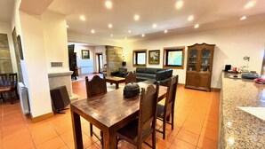 A spacious living room with a dining area, a stone fireplace, and a kitchen area with granite countertops.