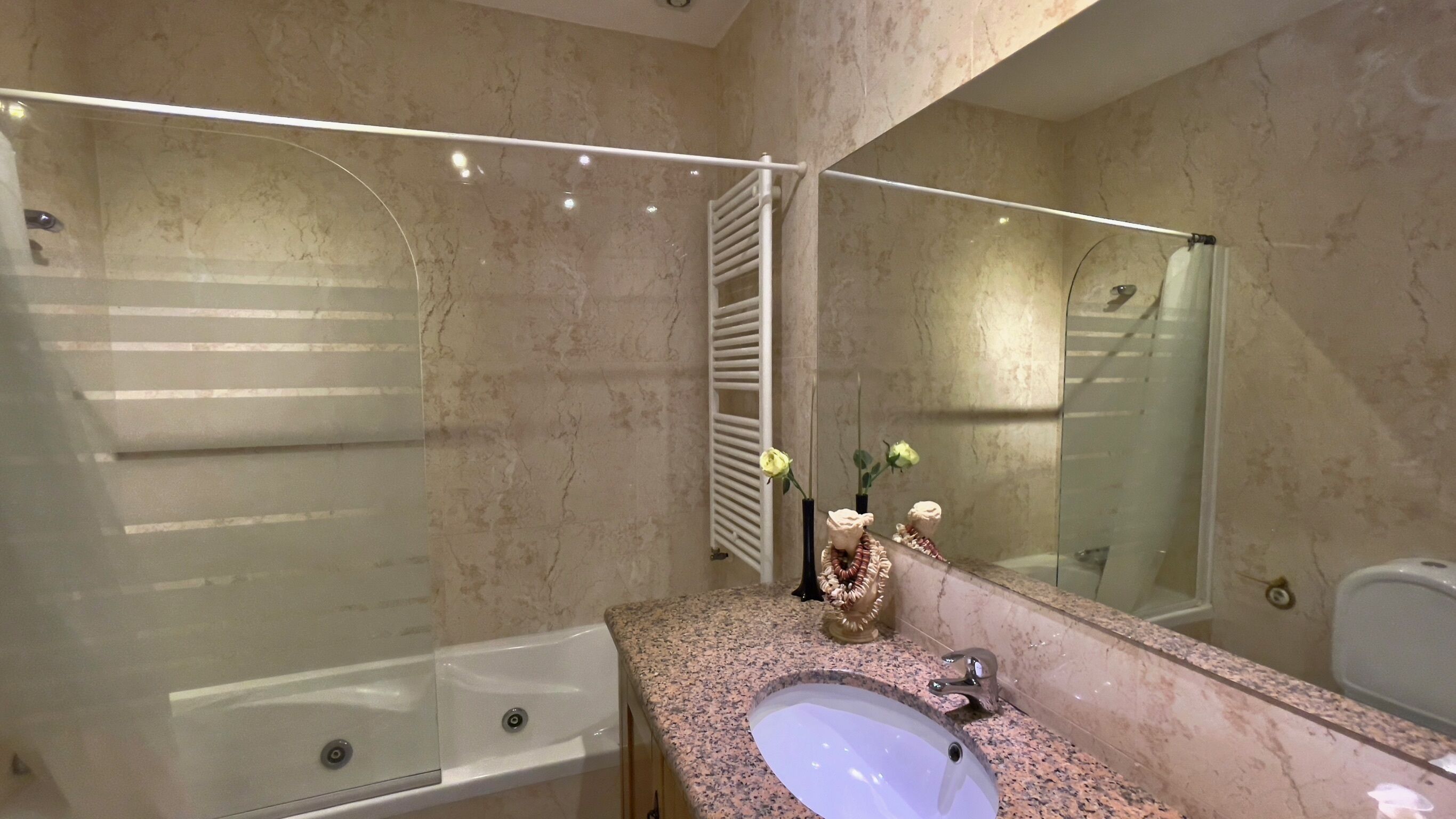 Une salle de bain moderne avec un grand miroir, une baignoire, un lavabo et une douche.