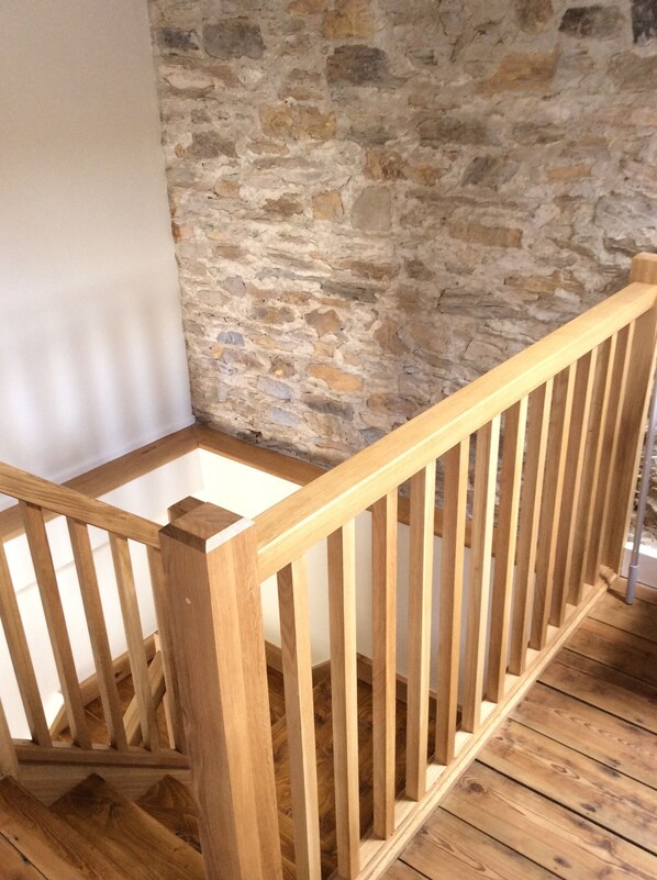 A wooden staircase with a stone wall background.