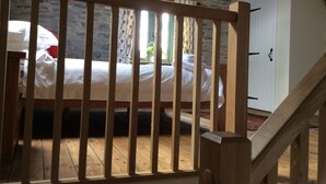 A bedroom with a wooden bed, a stone wall, and a staircase. - Romantic Rural Retreat, Ideal Base to Explore Cornwall (Wadebridge)