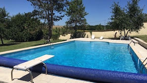 Une piscine rectangulaire dotée d’un plongeoir et d’une chaise longue.