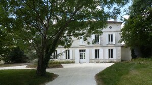 Un bâtiment à deux étages avec une allée de gravier menant à une porte blanche.