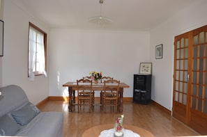 Un coin repas avec une table en bois, des chaises et un vase de fleurs. La pièce contient également un canapé et un meuble.
