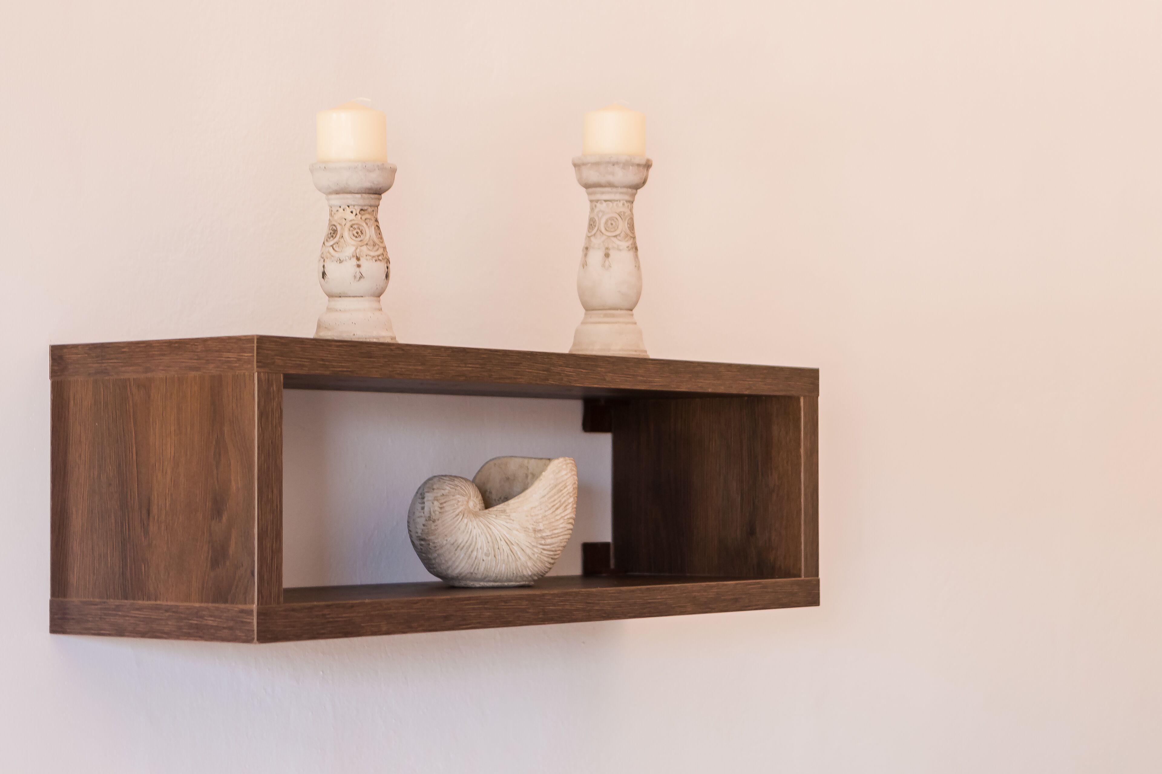Een houten plank met twee kaarsen en een schelpen ornament.