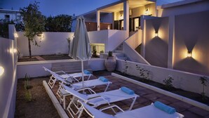 Une terrasse sur le toit avec des chaises longues, un grand vase et un escalier.