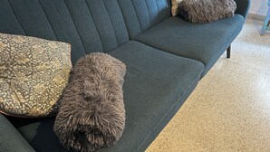 A dark blue sofa with three decorative pillows in a room with a tiled floor. - Nice apartment in the city center with parking. (Granada)