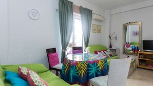 A room with a bed, a chair, a table with a colorful tablecloth, a television, and a mirror. - Nice apartment in the city center with parking. (Granada)