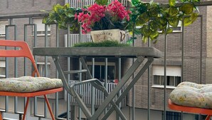 A balcony with a table, two chairs, and a potted plant with flowers. - Nice apartment in the city center with parking. (Granada)