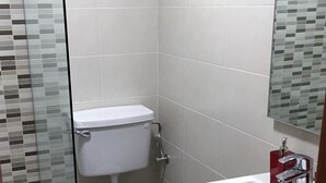 Un baño con inodoro, lavamanos y zona de ducha.