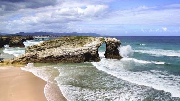 Un paysage côtier caractérisé par une formation rocheuse imposante, notamment une arche naturelle.