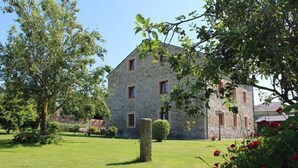Un bâtiment en pierre doté d’une pelouse et d’un jardin bien entretenus.