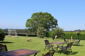 Un espace extérieur aménagé avec des tables et des chaises, un but de football et un grand arbre.