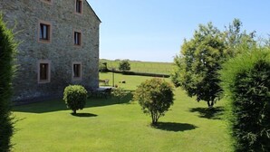 Un bâtiment en pierre doté de nombreuses fenêtres et d’une pelouse bien entretenue, agrémentée de quelques arbres.