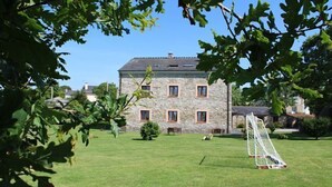 Un bâtiment en pierre avec une cour gazonnée et un but de football.