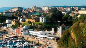 Une ville côtière dotée d’un port de plaisance, de bâtiments historiques et offrant une vue panoramique depuis une colline.