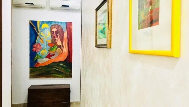 Un pasillo decorado con obras de arte, un banco de madera y unidades de aire acondicionado.