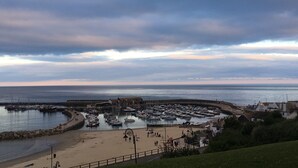 A coastal town with a marina, sandy beach, and a promenade.