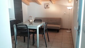Un espacio habitable compacto con una mesa y sillas de comedor, un sofá y una lámpara.