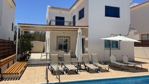 A modern building with a pool, outdoor seating, and a covered patio area.
