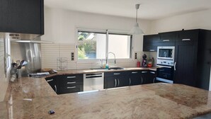 A modern kitchen with a granite countertop, stainless steel appliances, and black cabinetry. - superb house ideally located 220 m2 (Sainte-Sève)