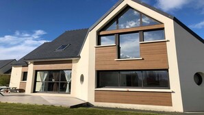 A modern two-story house with a sloped roof, large windows, and a visible garage door. - superb house ideally located 220 m2 (Sainte-Sève)