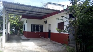 Un edificio con fachada roja y blanca, un vestíbulo cubierto y suelo de concreto.