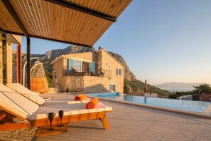 A stone building with a pool, lounge chairs, and a view of mountains. - Villa Jatica - Luxury in the Wilderness of Makarska (Gradac)