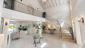 Un intérieur spacieux comprenant un escalier, un coin salon et un téléviseur.