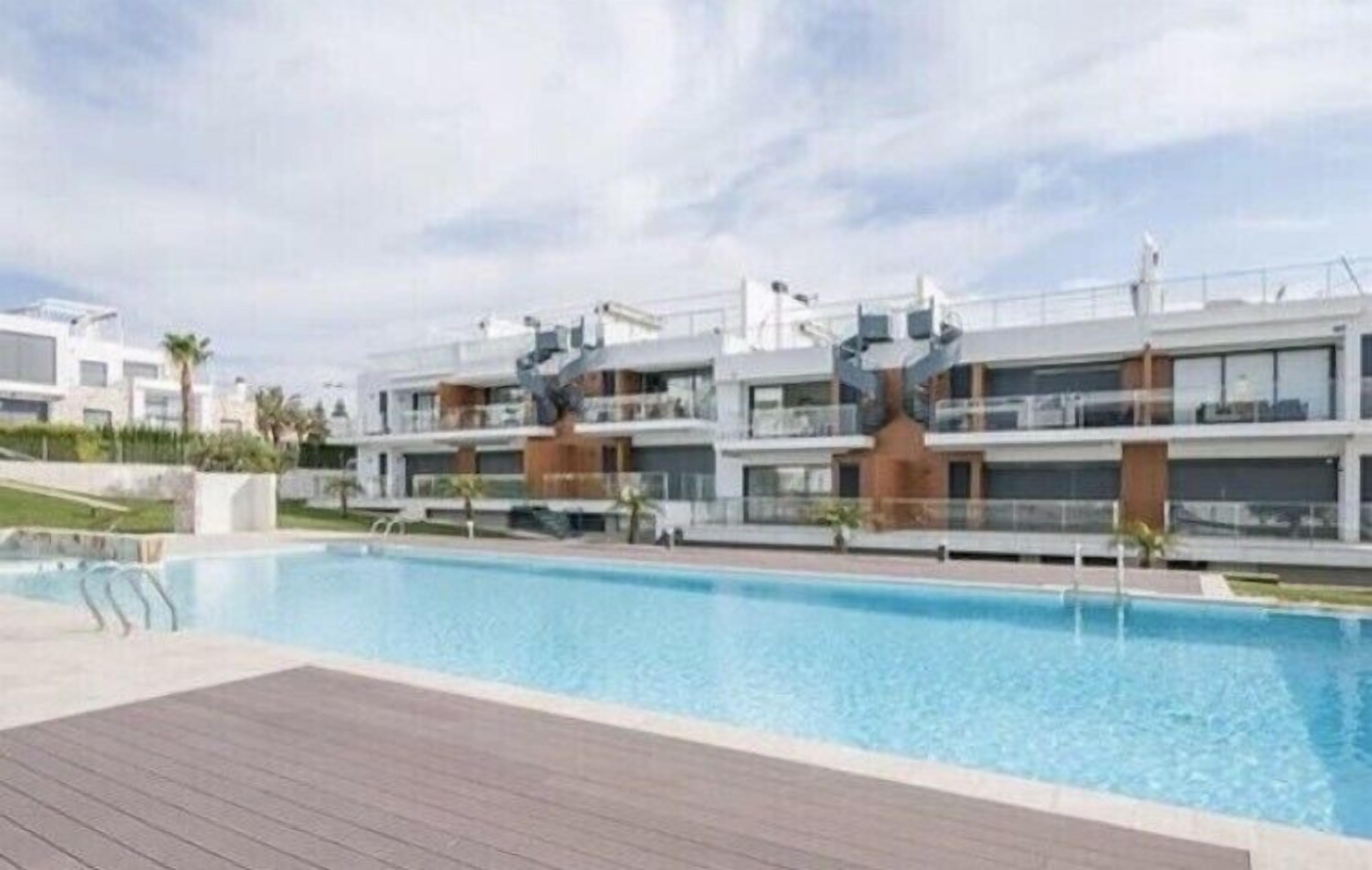 Un edificio residencial moderno con piscina, que cuenta con varios balcones y un diseño contemporáneo.
