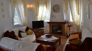 A living room with a fireplace, a television, and a sofa set.