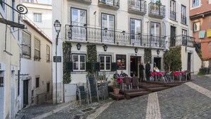 Ein Gebäude mit Innenhof, Außenbestuhlung und einer Treppe, die zum Eingang führt.