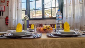 A dining table set with plates, cutlery, a water bottle, and a fruit bowl. - Wonderful View Apartment with Fantastic sunsets (Florenças, Arco da Calheta)