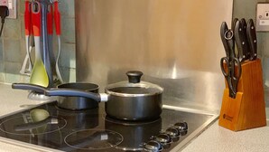 Una cocina con estufa, ollas y un bloque de cuchillos.