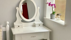 Una cómoda blanca con espejo, un cajón y un taburete.