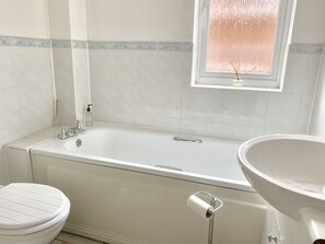 A bathroom with a bathtub, toilet, and sink.