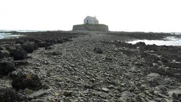 Een gebouw aan een rotsachtige kustlijn met vrij uitzicht op zee.