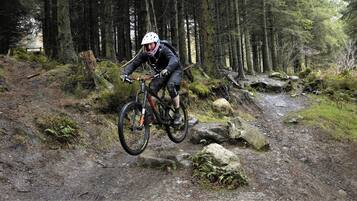 A mountain biker navigating a rocky trail in a forested area.