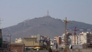 A hilly urban area with buildings, a construction crane, and a prominent tower on the hill. - Apartment Fira HUTB-014228 (L'Hospitalet de Llobregat)