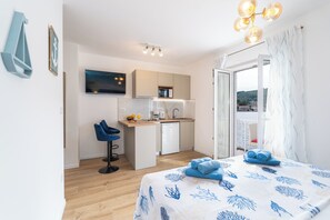 Cozy retreat with a single bed, sitting area, and kitchenette, offering a balcony with a view.