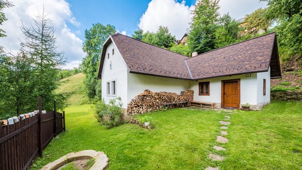 A white house with a brown roof, a wooden door, and a stone pathway leading to the entrance. - Country house Fort Lacnov (Lipovce)