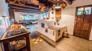 A kitchen with a stove, wooden cabinets, and hanging pots. - Country house Fort Lacnov (Lipovce)