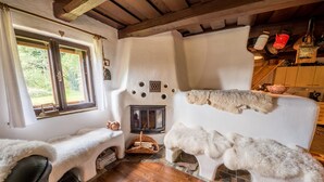 A cozy room with a fireplace, a fur-covered bench, and a rustic wooden ceiling. - Country house Fort Lacnov (Lipovce)