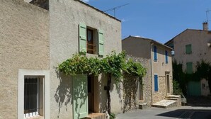 A narrow street with traditional stone buildings, each with a small entrance and a window with shutters. - Lou Marcelou - Apartment One (Sainte-Croix-du-Verdon)