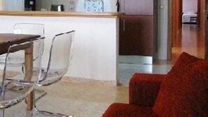A modern kitchen with white cabinets, a microwave, and a refrigerator. There is a dining area with a table and chairs. - Apartment/ flat - Plasencia (Plasencia)