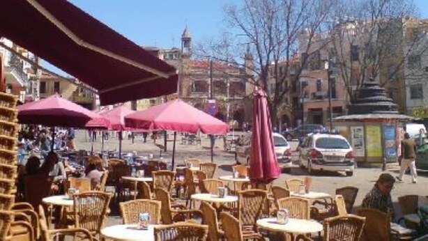 Outdoor seating with tables and chairs, umbrellas, and a street view with buildings and cars. - Apartment/ flat - Plasencia (Plasencia)
