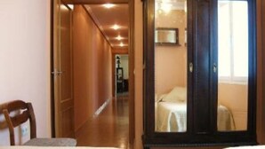 A hotel room with a wooden wardrobe, a bed with a white bedspread, and a chair. - Apartment/ flat - Plasencia (Plasencia)