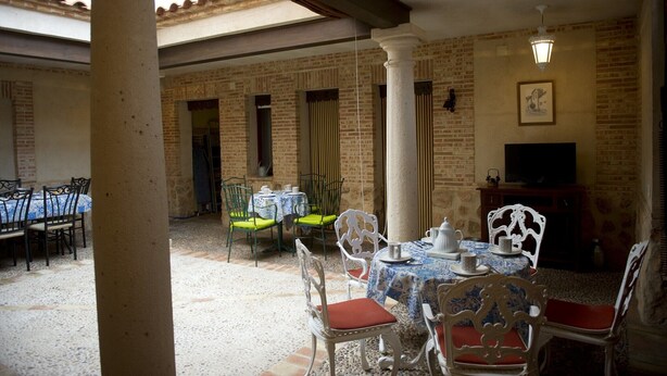 A covered outdoor dining area with brick walls, white columns, and tables set for dining. - Rural House La Biblioteca. 6hab=350€- 7hab=390€ (Almagro)