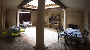 A spacious dining area with a high ceiling, a central column, and a view through an open door to an adjacent room. - Rural House La Biblioteca. 6hab=350€- 7hab=390€ (Almagro)